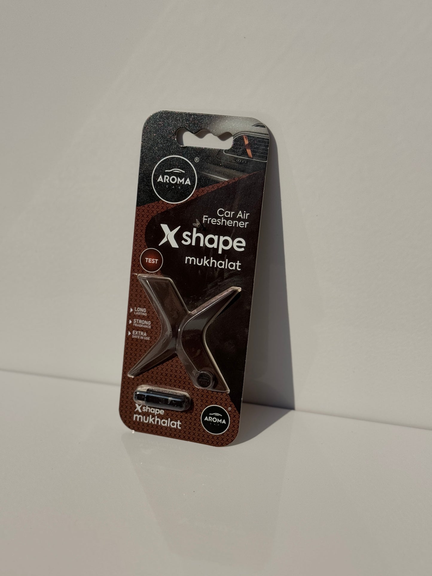 Aroma Car X-Shape Air Fragrance placed on a car ventilation grill, emitting a refreshing French perfume scent.