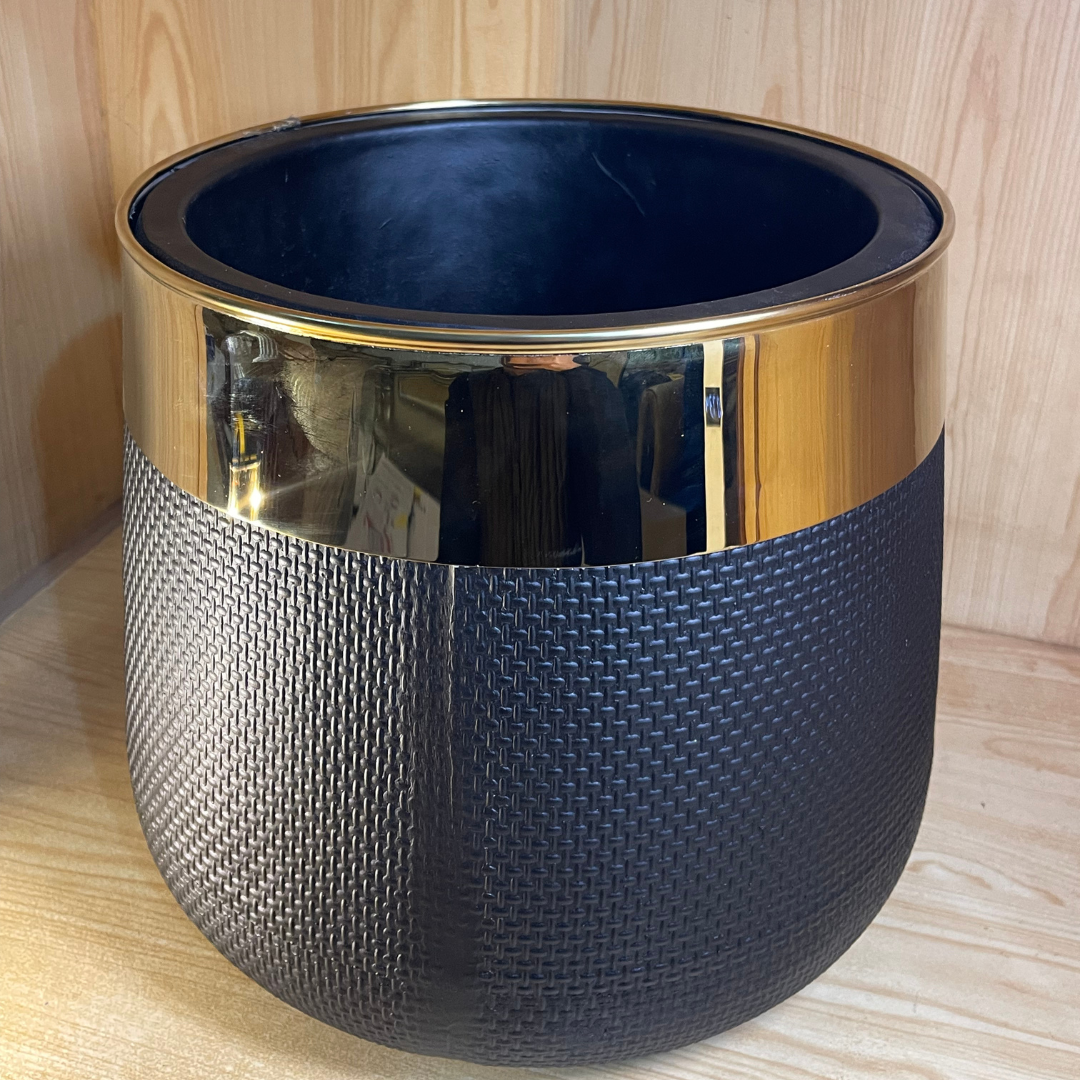 Black fiber flower pot and planter placed in a modern living room corner with vibrant indoor plants.