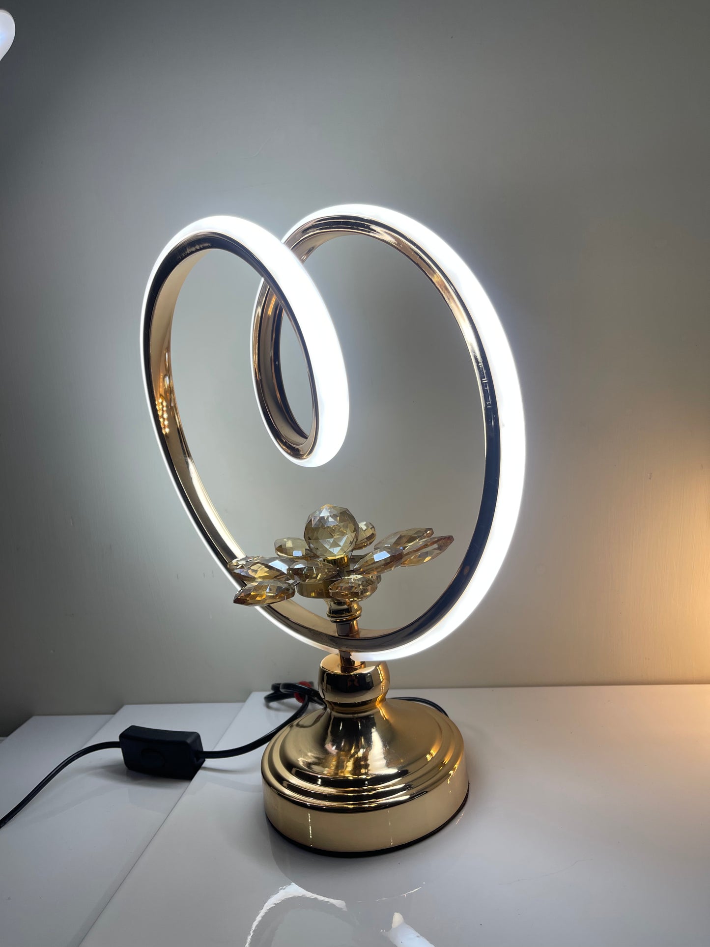 Elegant circle lamp with flower base displayed on a side table in a modern living room.