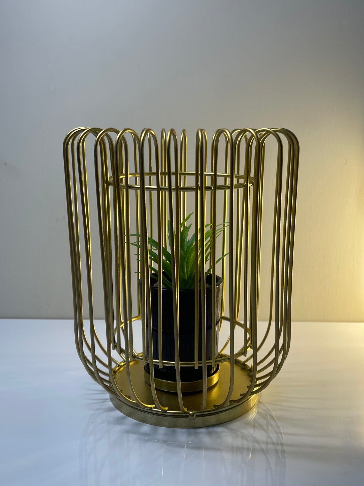 Side view of a gold metal cage planter featuring a realistic faux succulent.