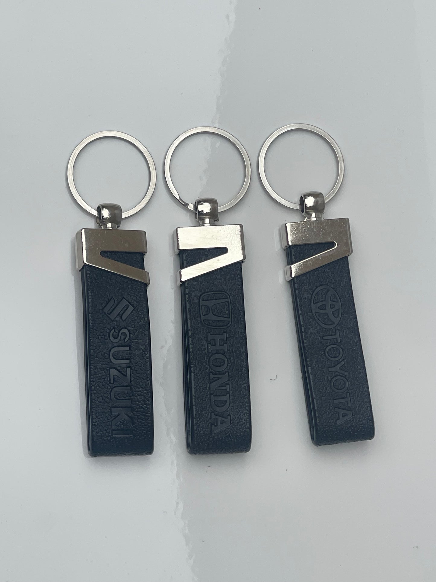 Honda and Suzuki logo keychains displayed together, showcasing stylish and high-quality craftsmanship.