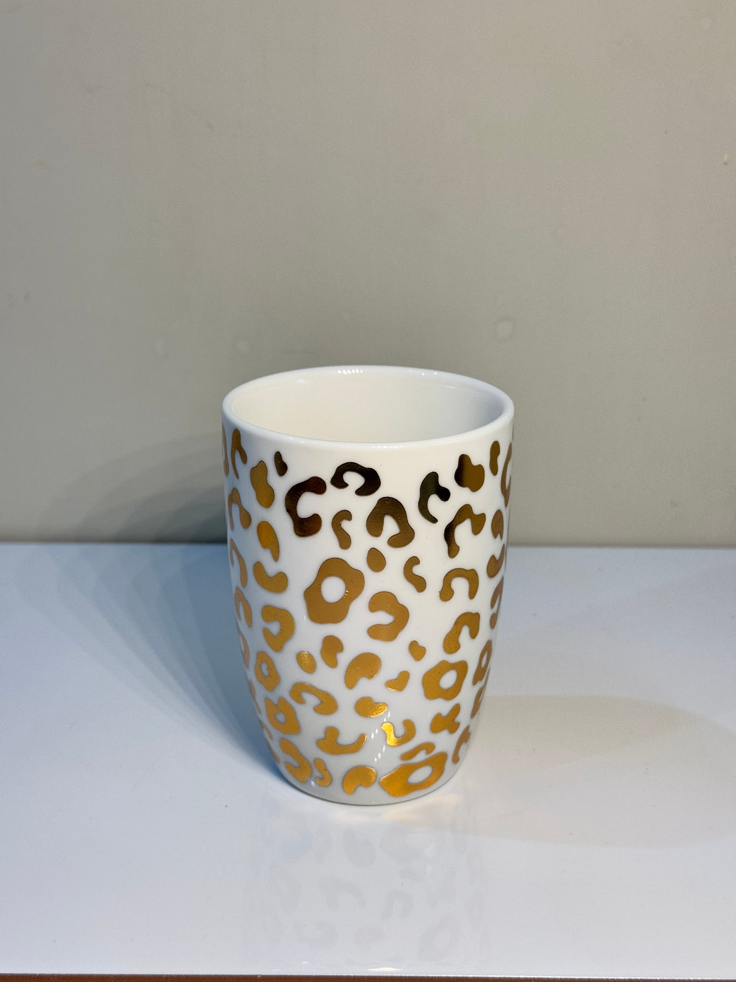 White and gold ceramic tumbler with cheetah print, perfect for bathroom essentials.