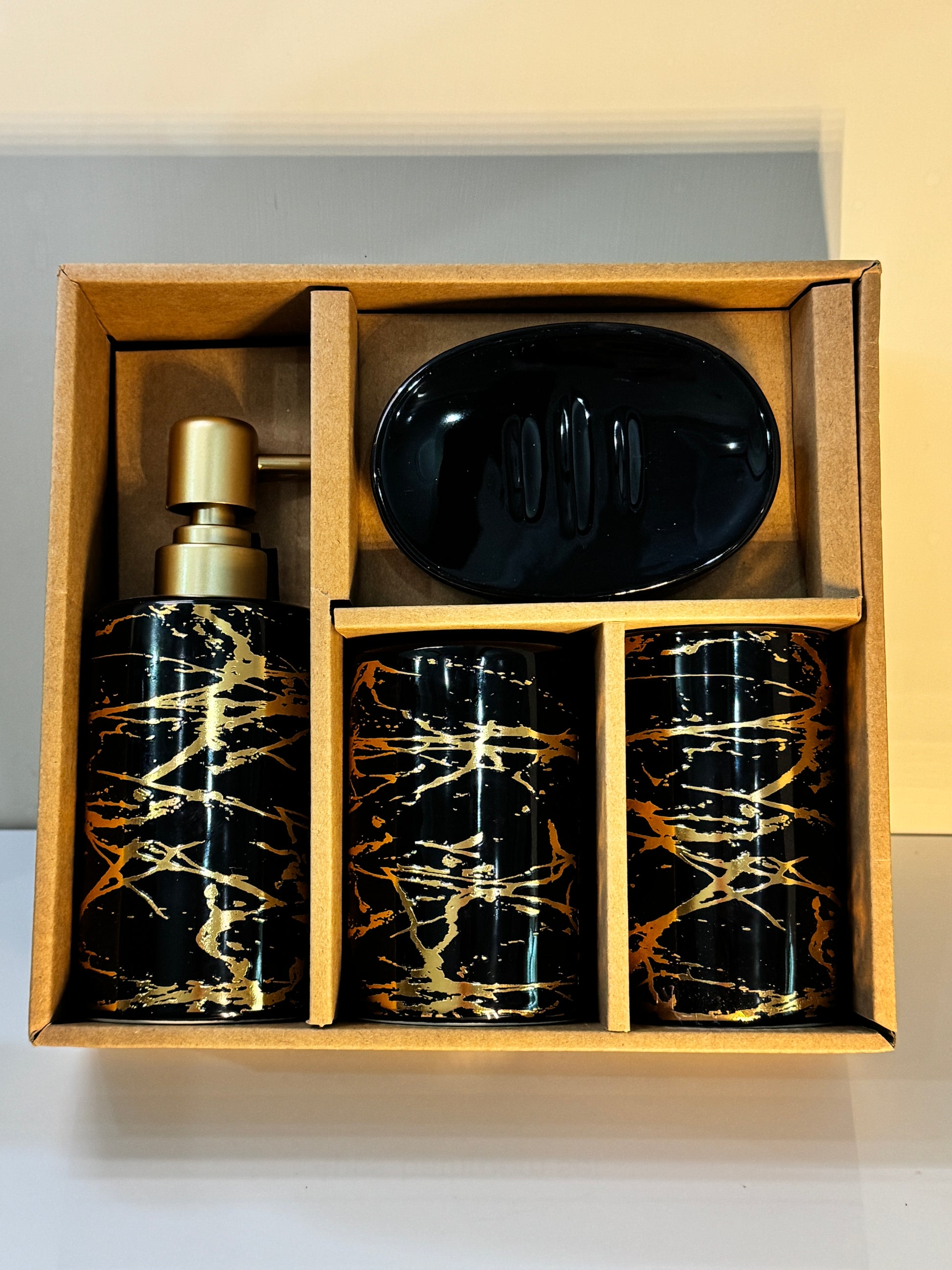 4-piece ceramic bathroom accessories set securely packaged in a sturdy box, showcasing the glossy black and gold designs.