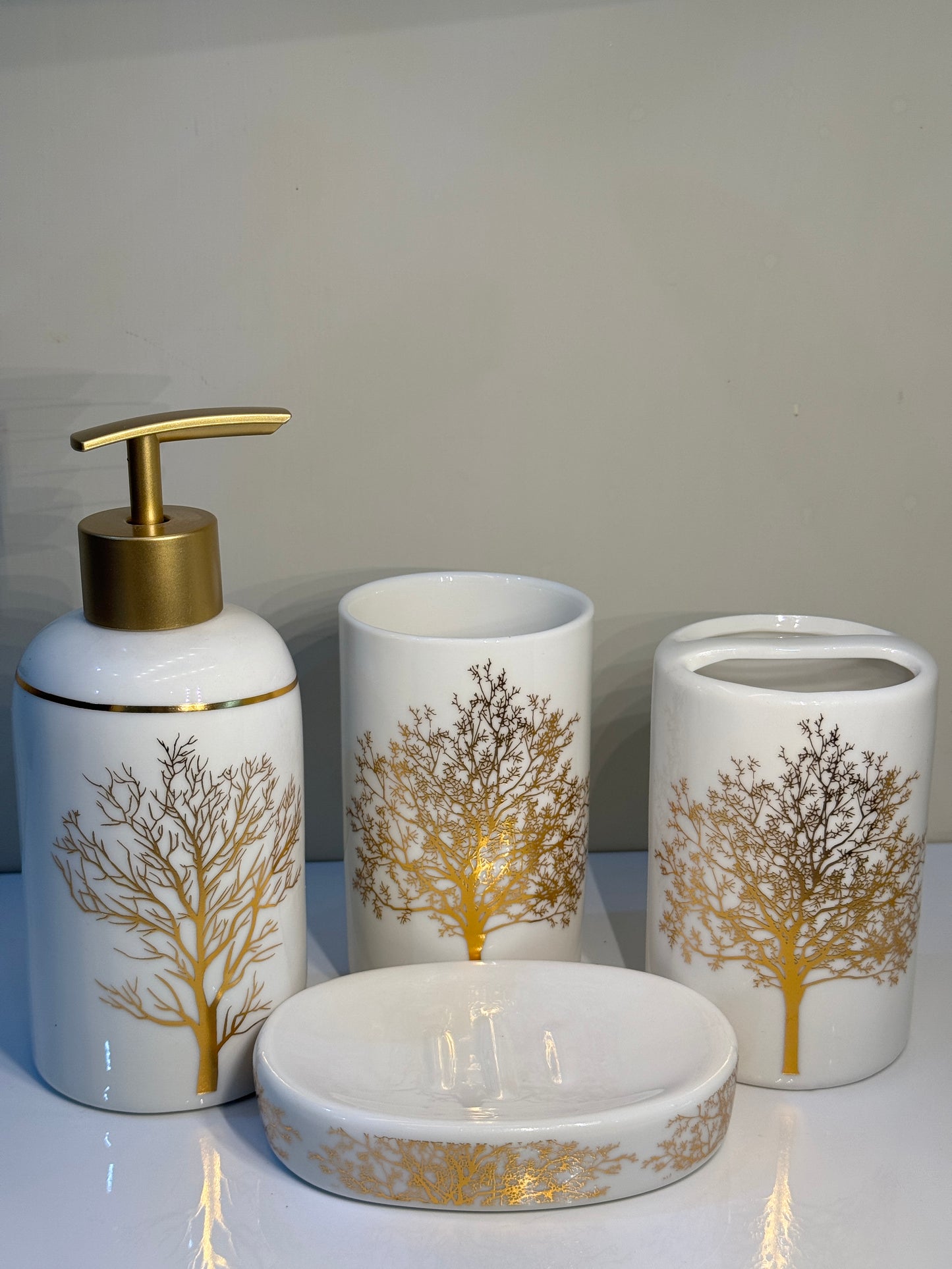 4-piece ceramic bathroom set in white and gold with a unique round design, displayed on a countertop.