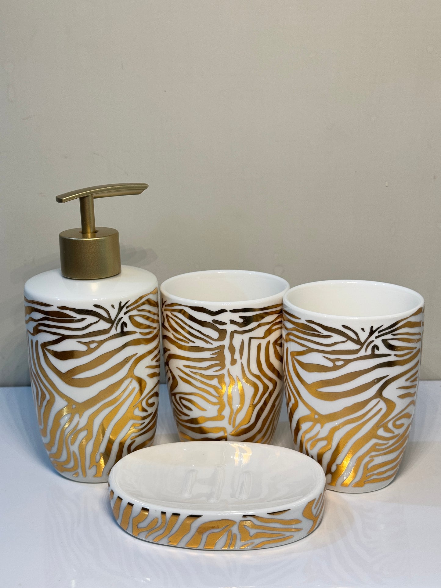 4-piece tiger print ceramic bathroom set in glossy black, including soap dispenser, tumbler, toothbrush holder, and soap dish.