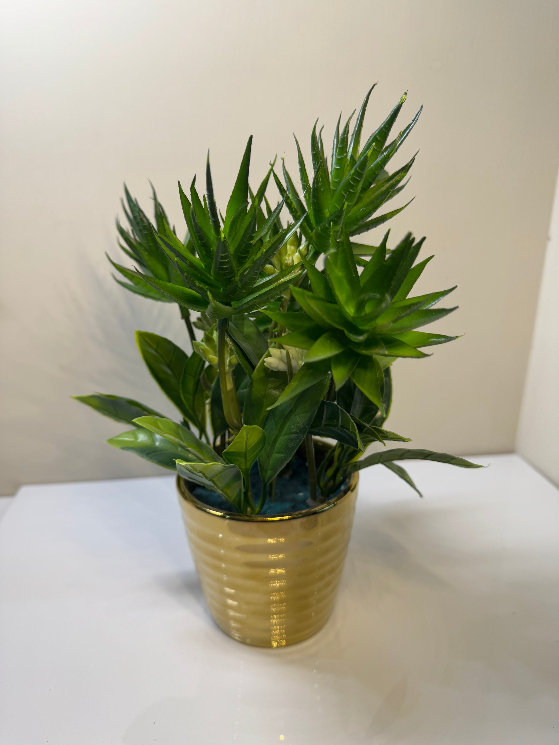 Artificial plant in a gold-colored glass pot, showcasing its elegant and modern design.