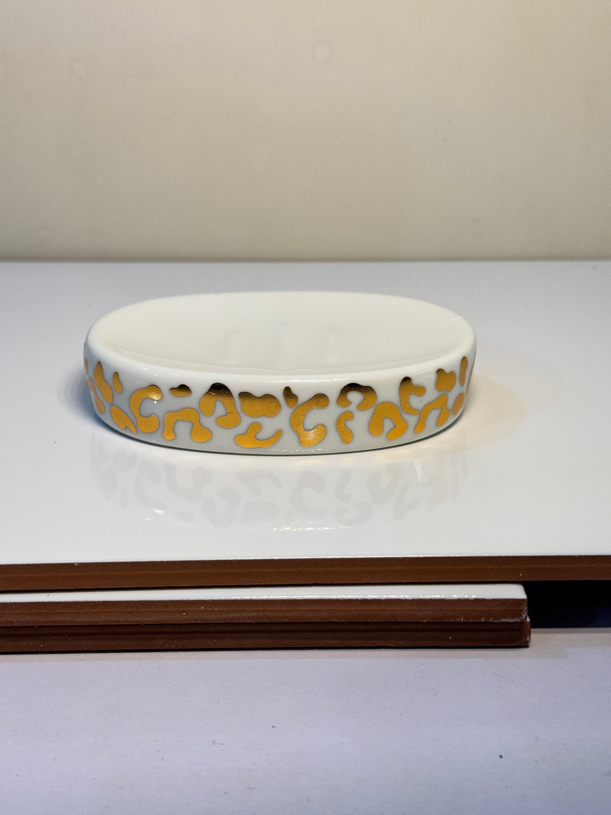 Ceramic soap dish featuring a chic cheetah print in white and gold, ideal for keeping soap dry.