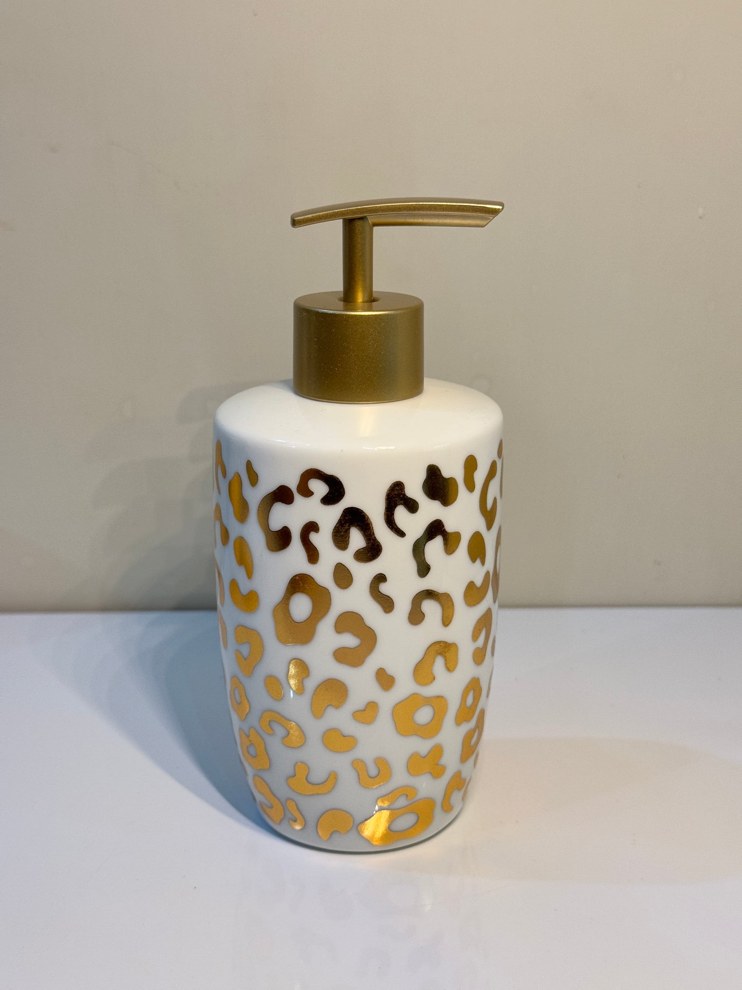 Ceramic soap dispenser with a sturdy metal pump and Cheetah print design in white and metallic gold.