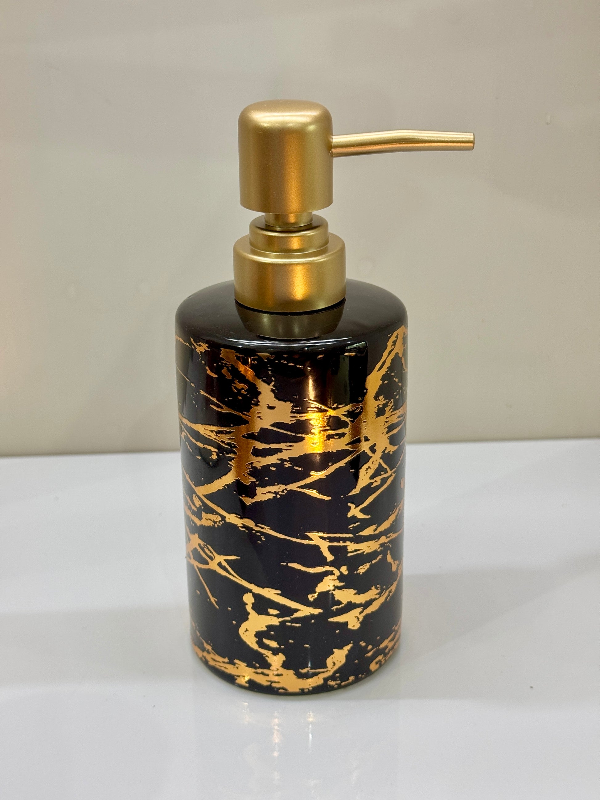 Glossy ceramic soap dispenser with a sleek black and gold design, perfect for modern bathrooms.