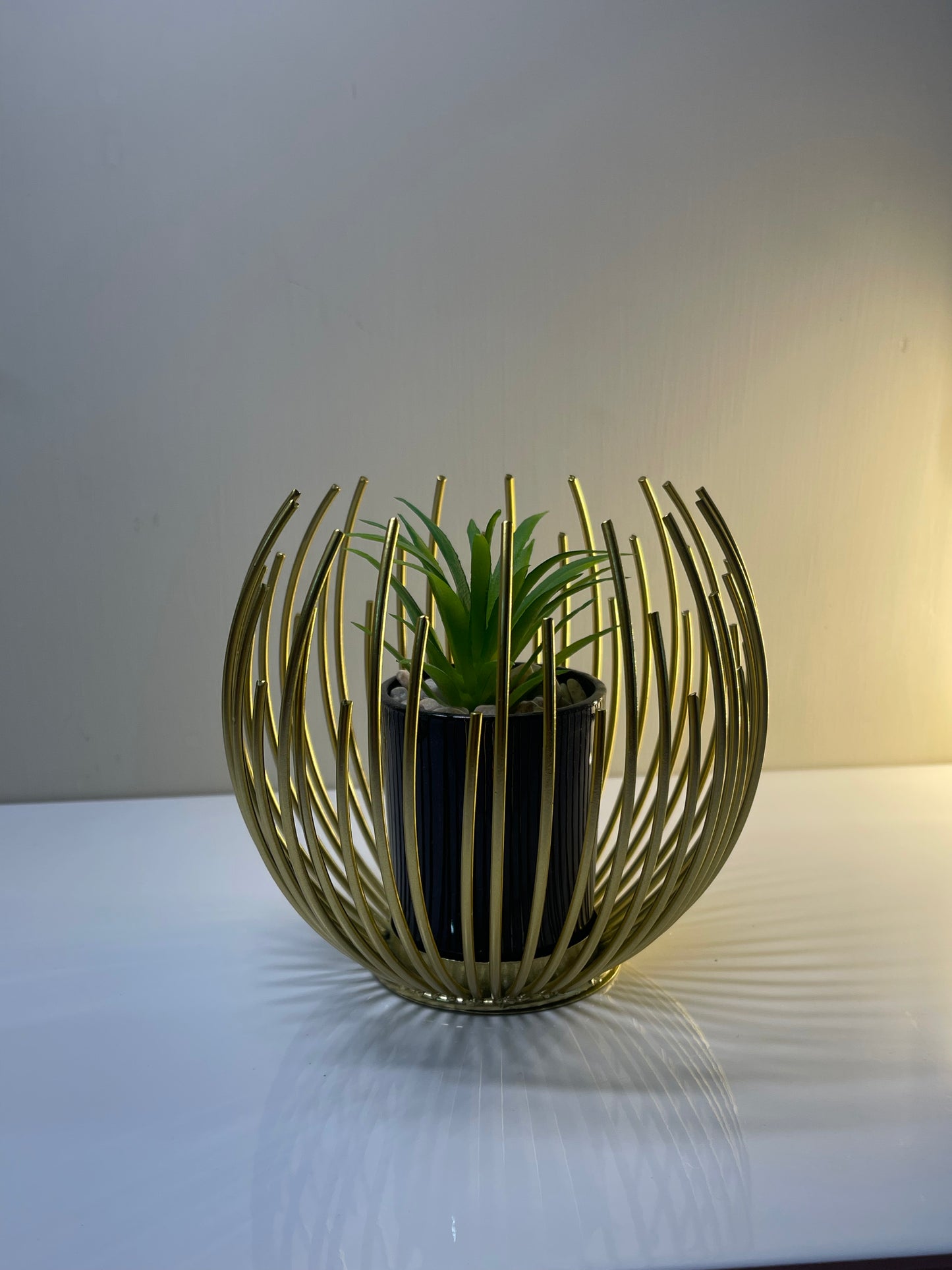 Golden globe planter holding a plant, showcasing its elegant design.