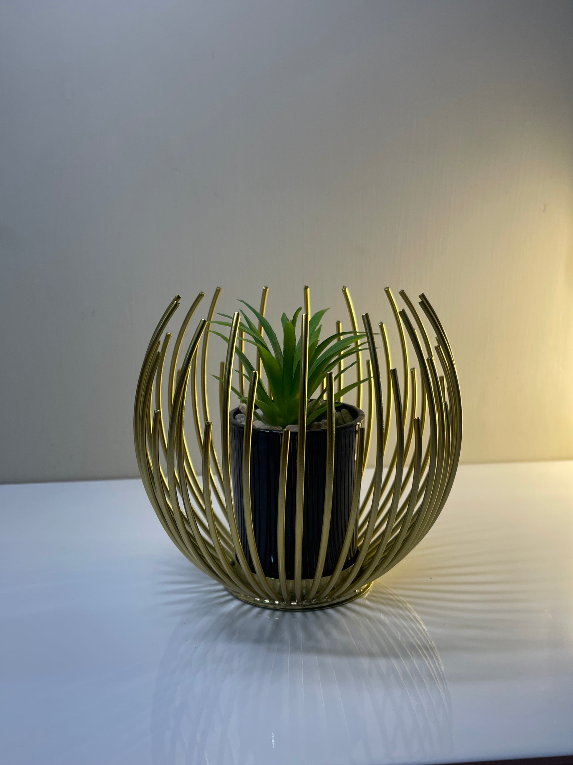 Golden globe planter holding a plant, showcasing its elegant design.