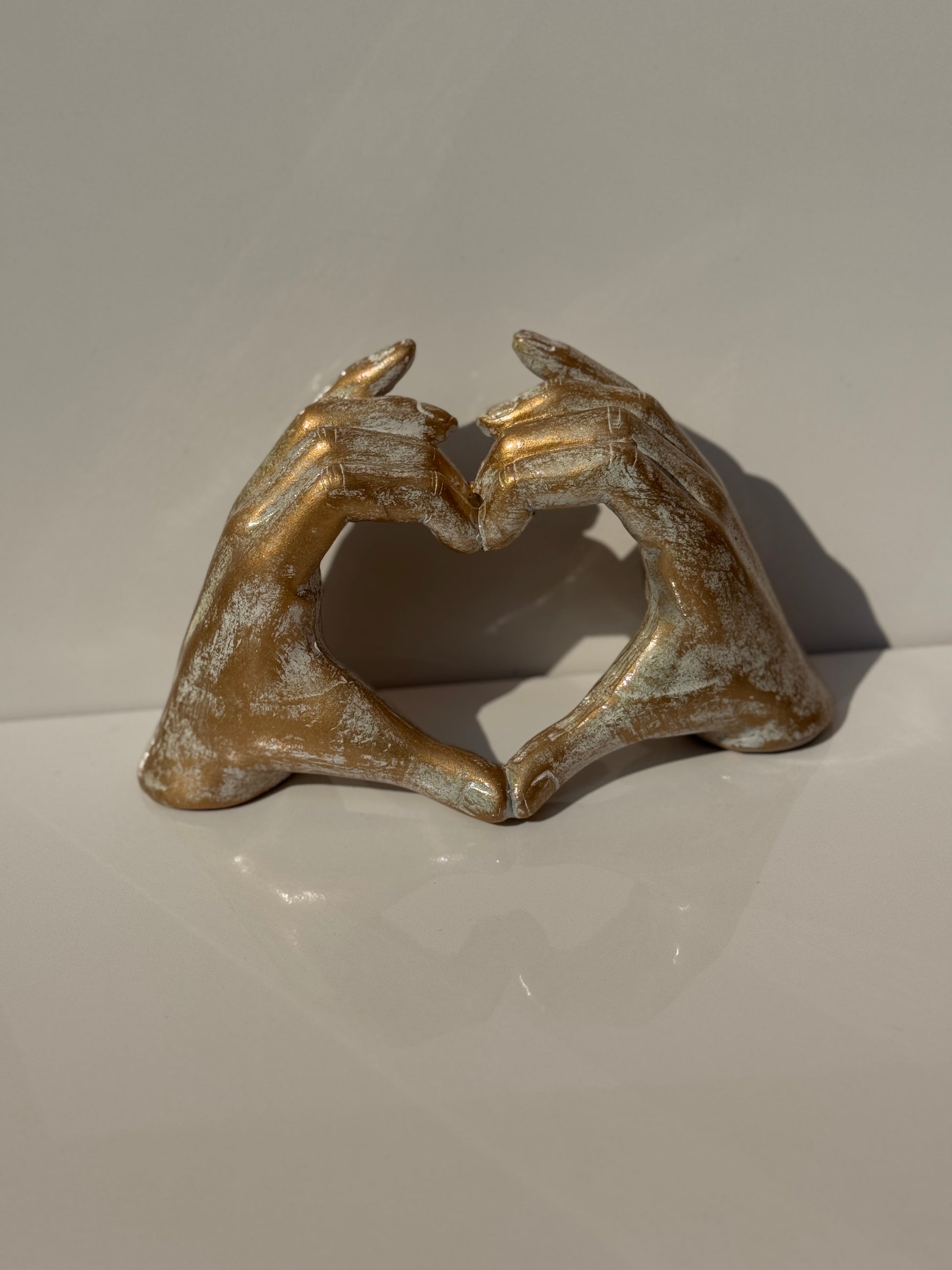 Love Sign Figure in gold finish, featuring a hand gesture forming a heart.