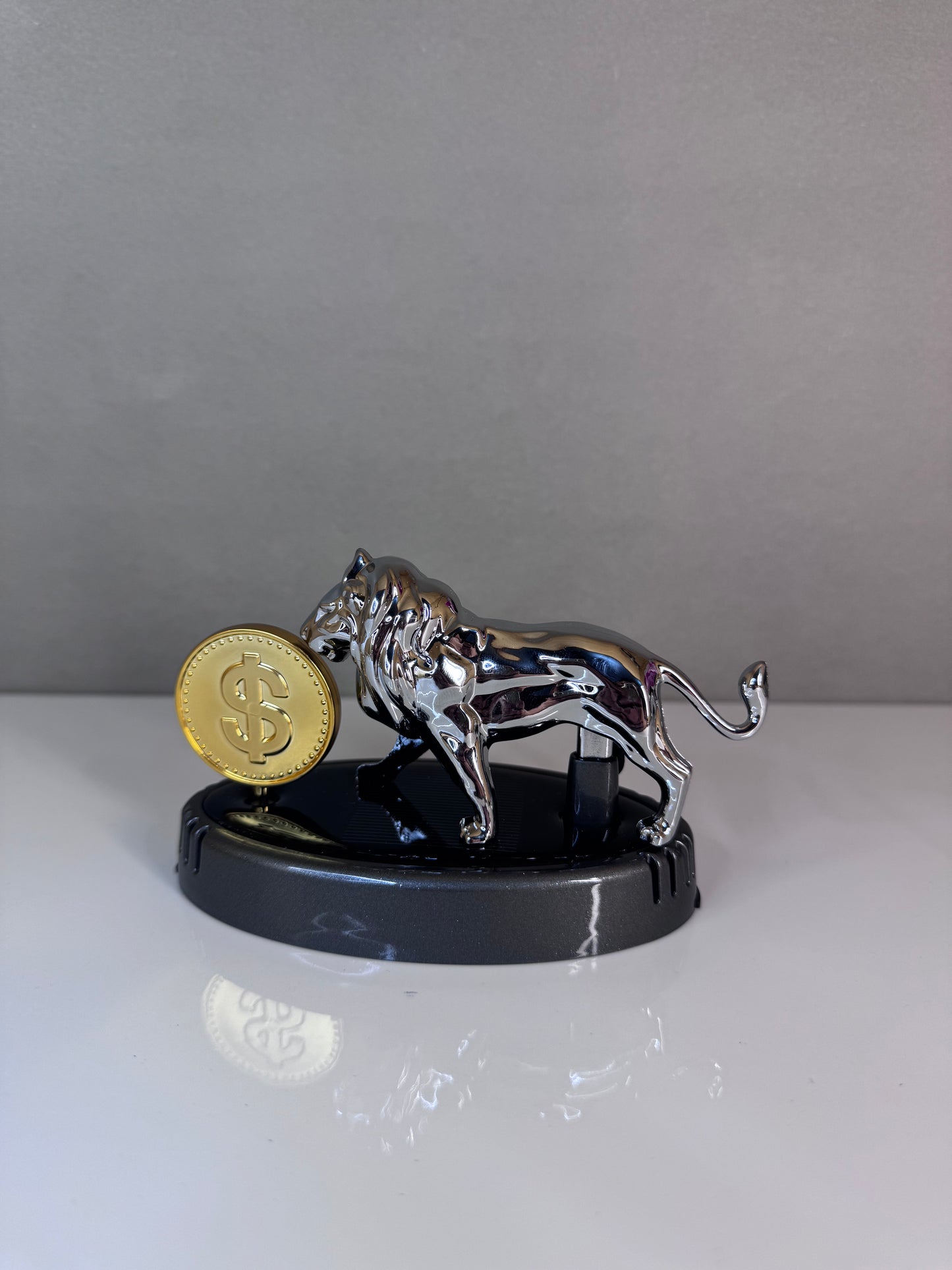 Metallic tiger figurine with a gold coin on a reflective surface