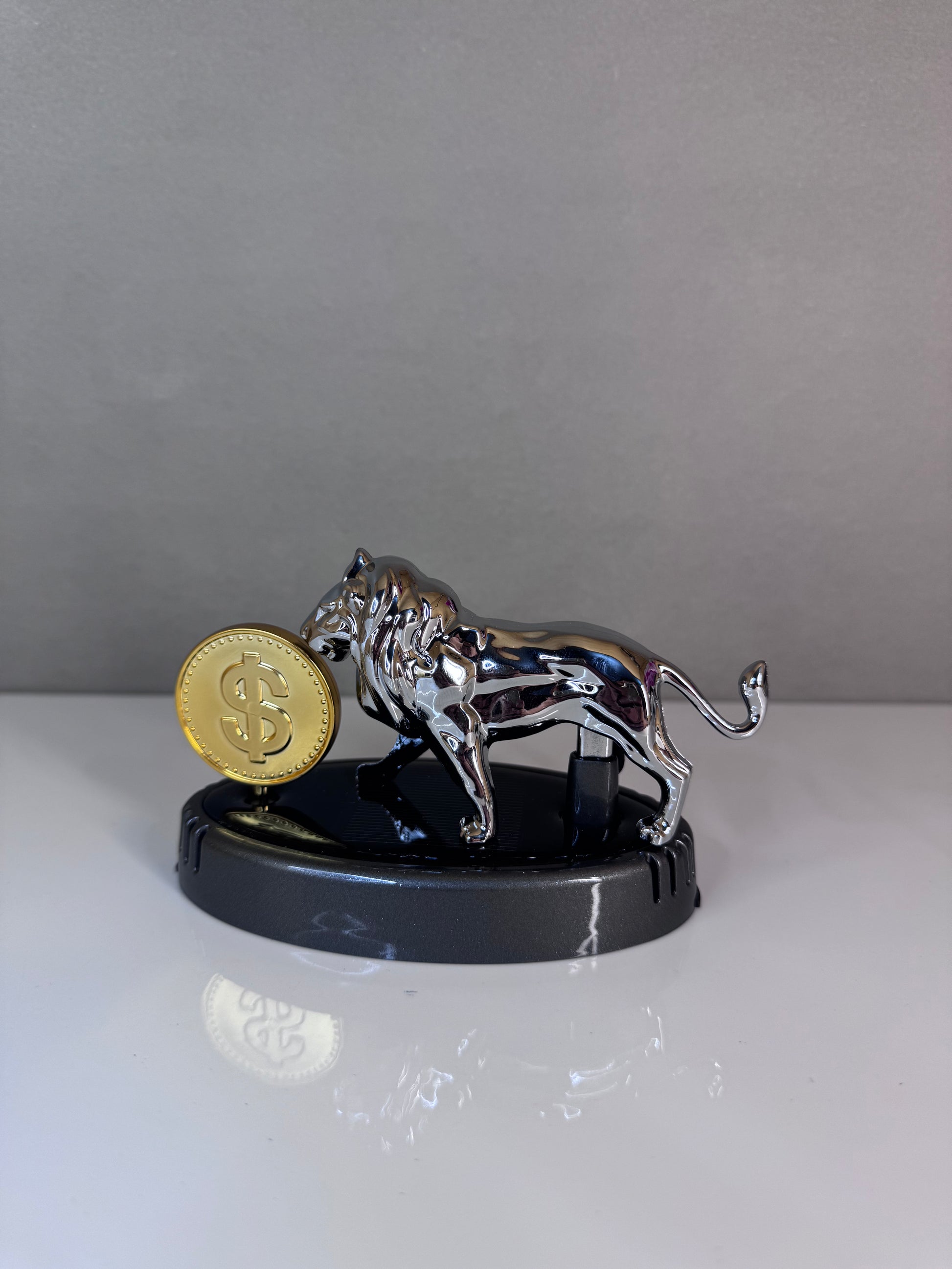 Metallic tiger figurine with a gold coin on a reflective surface