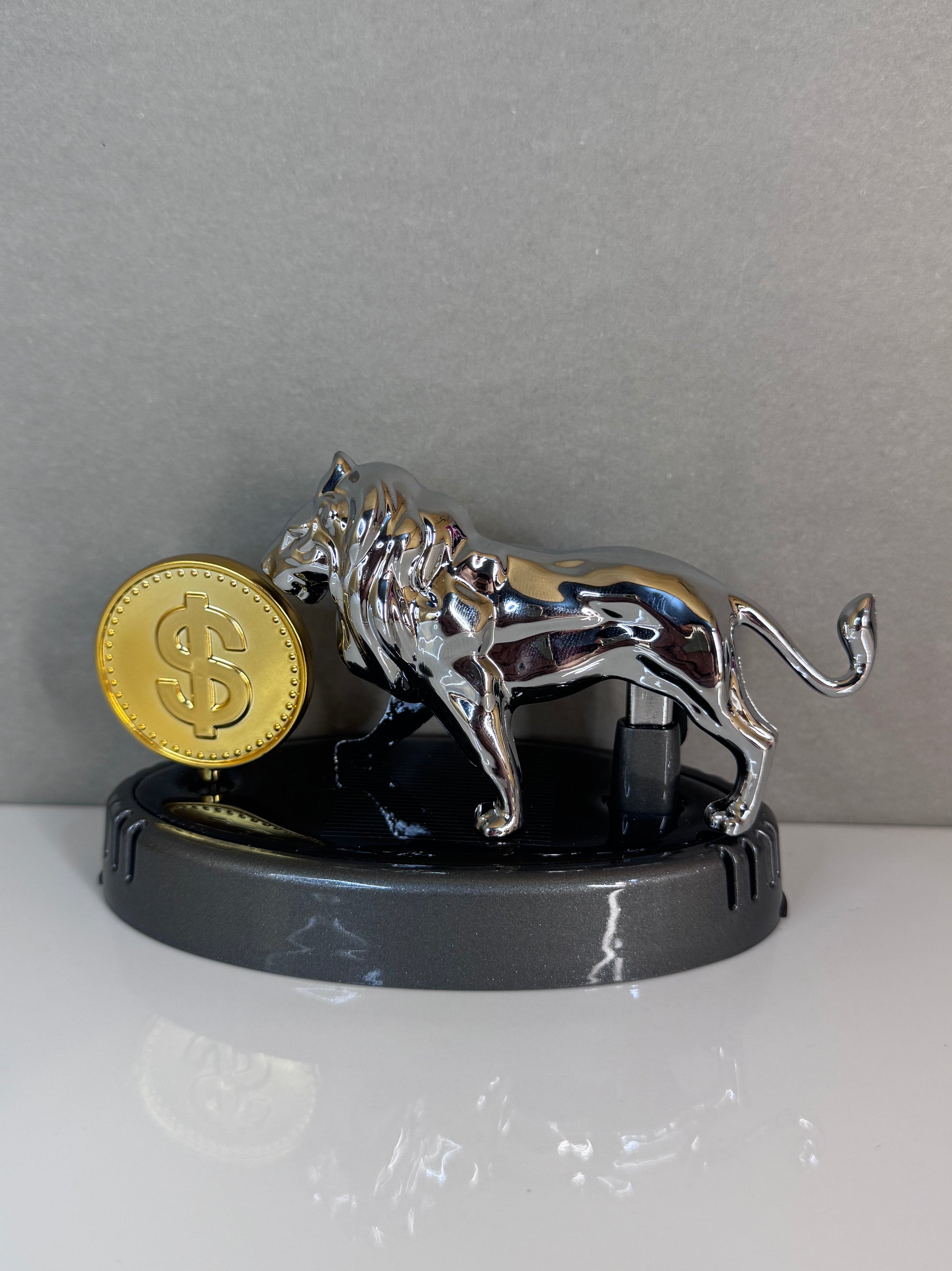 Metallic tiger figurine with a gold coin on a gray background