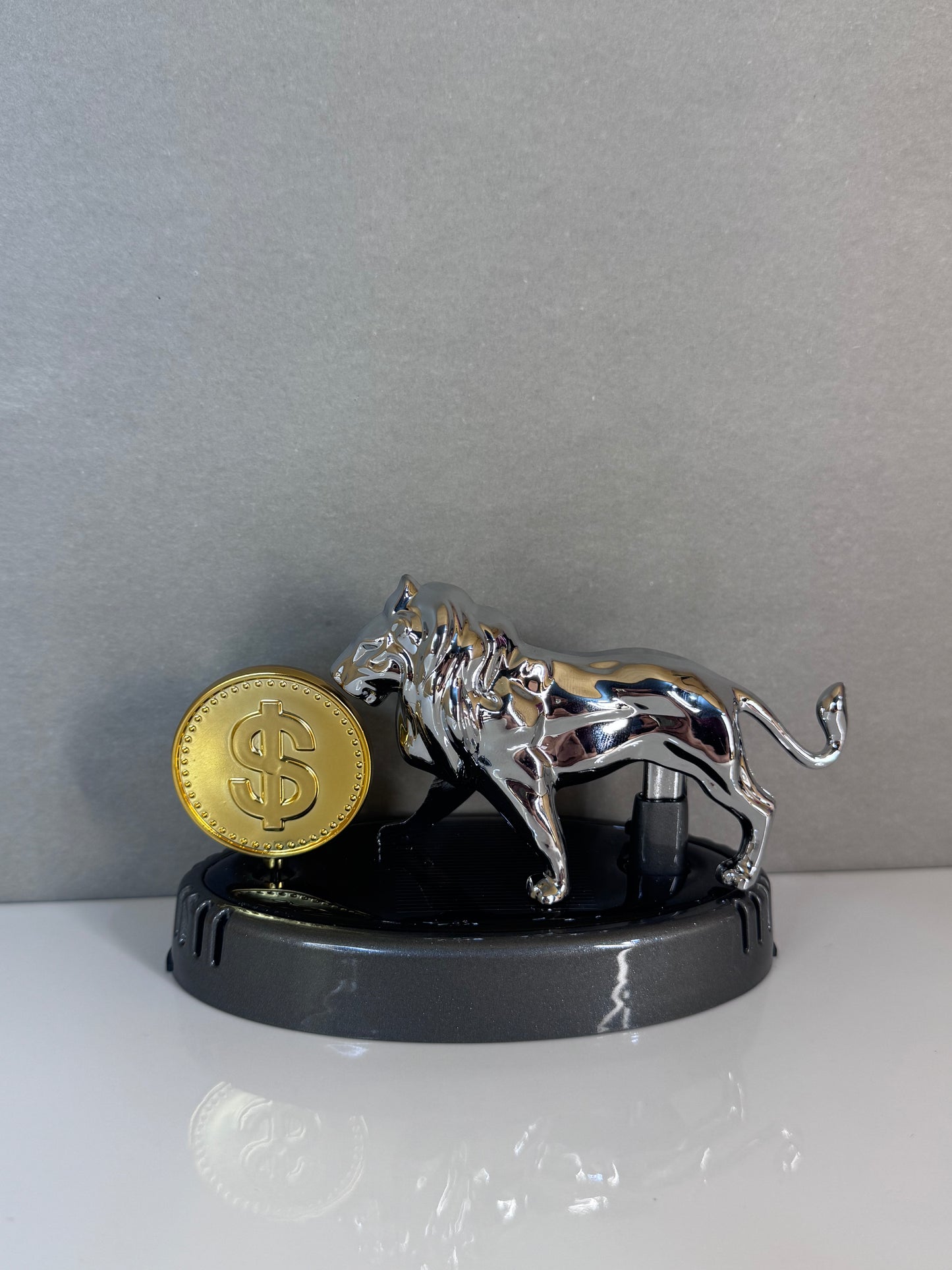 Metallic tiger figurine with a gold coin on a gray background