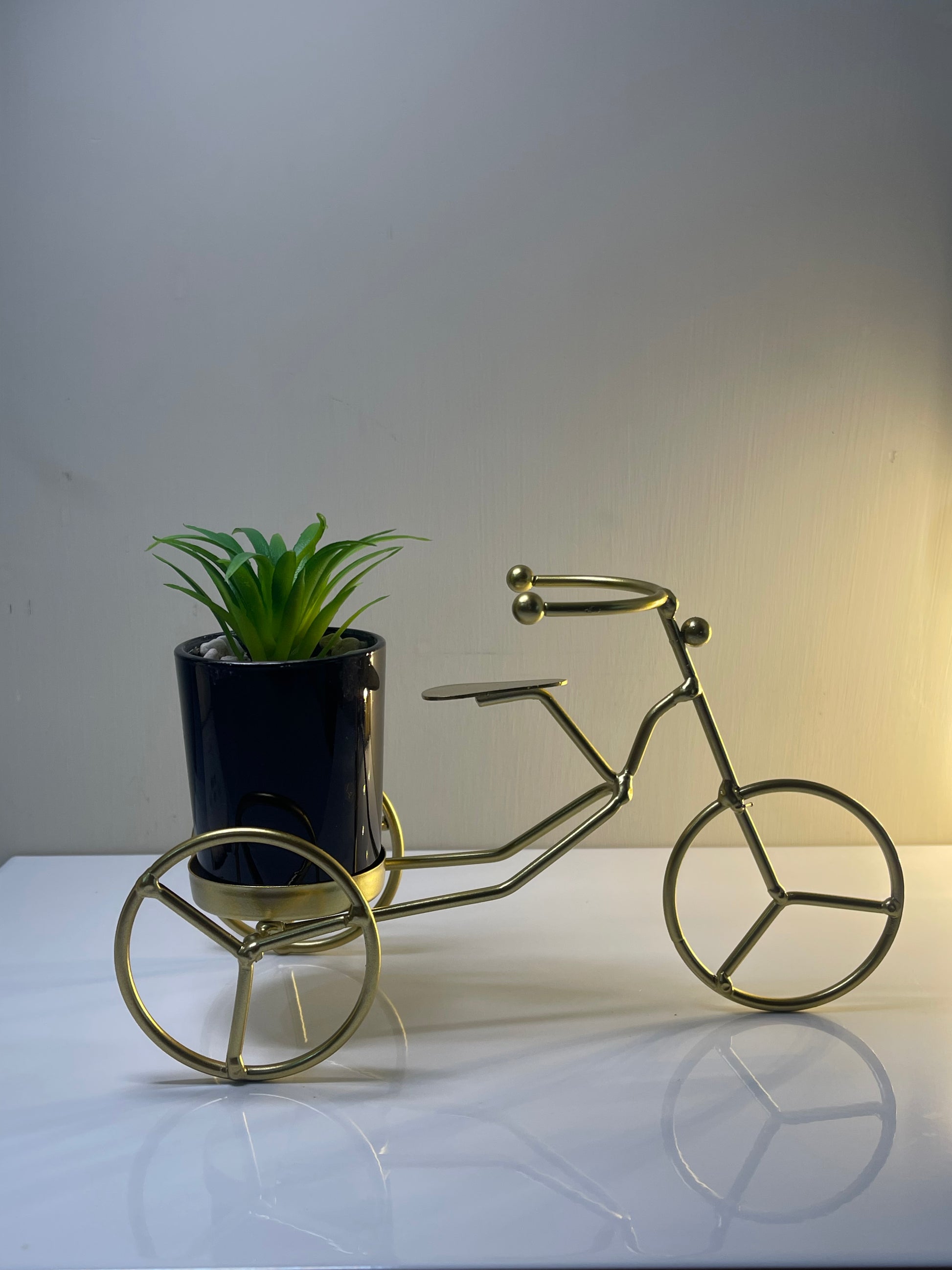 Solid metal cycle planter with black ceramic pot and gold accents.
