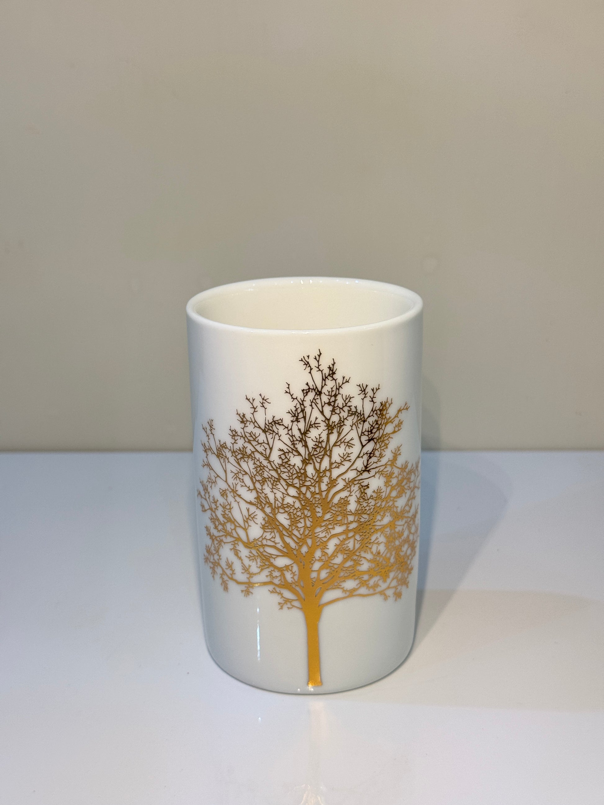 Versatile ceramic tumbler with a glossy white and gold finish, perfect for rinsing or storage.