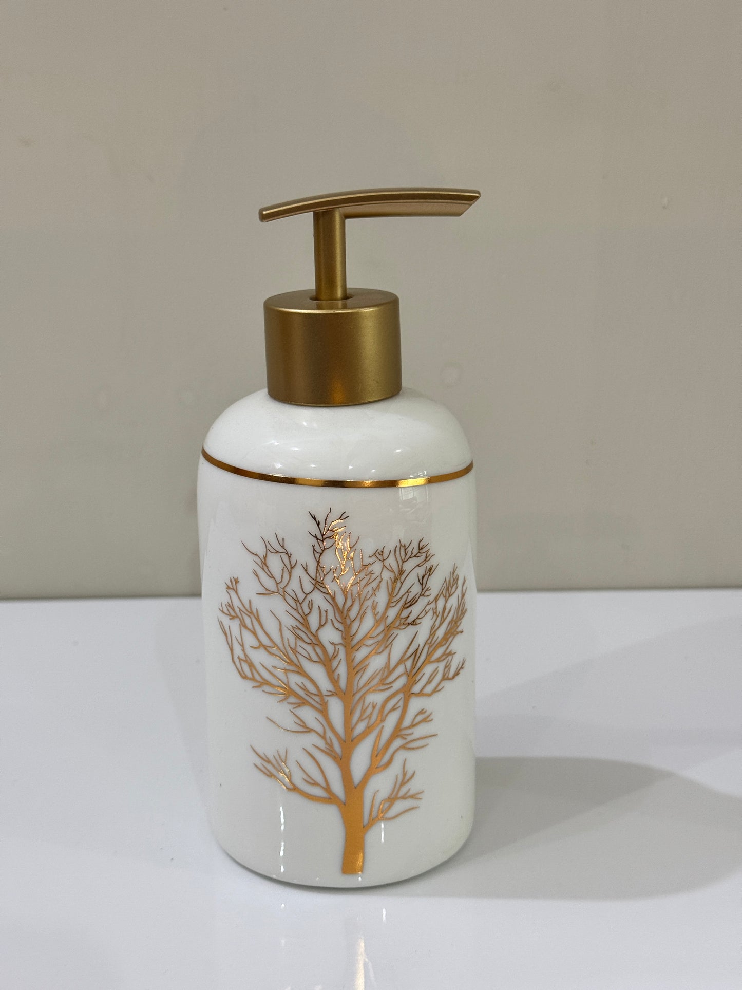 White and gold ceramic soap dispenser with a sleek round shape, ideal for liquid soap or lotion.